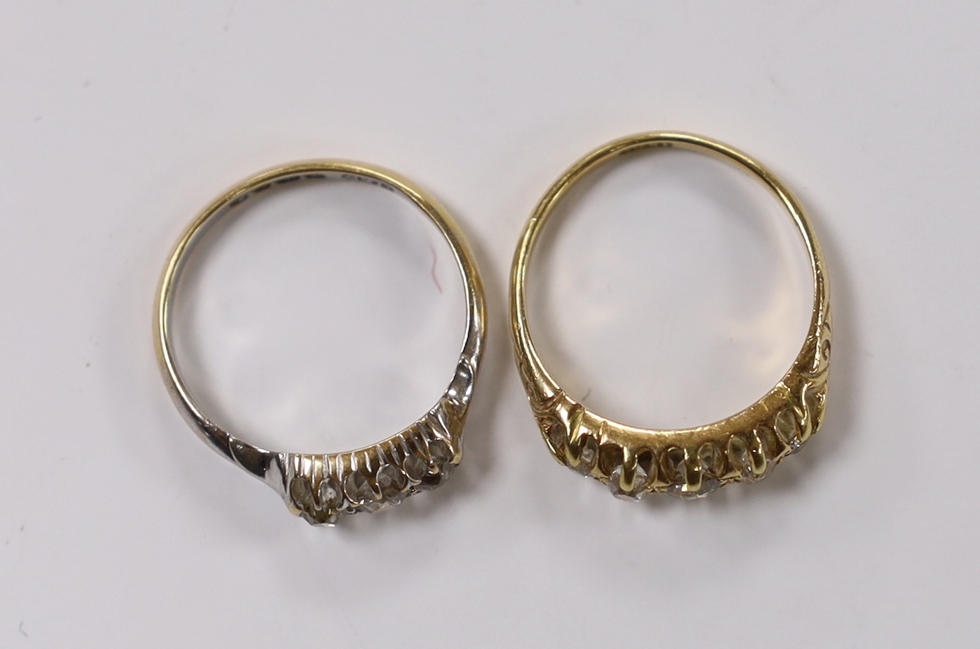 An early 20th century 18ct and claw set graduated old cut diamond half hoop ring, size N and an Edwardian 18ct white gold and three stone old cur diamond set ring, size N, gross weight 6.1 grams.
